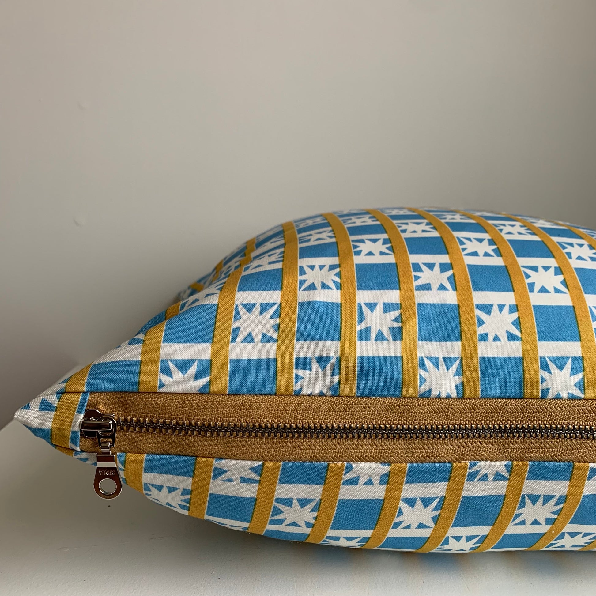 Handcrafted in Canada, this lovely cottage blue with white starburst fabric is gorgeous! Made from GOTS certified organic cotton. It's soft to the touch with an exposed mustard coloured zipper adding a another pop of colour to this beautiful fabric. Add a retro touch  to your home, cottage, bunkie, or sunroom. Sizes 18 x 18 and 12 x 20