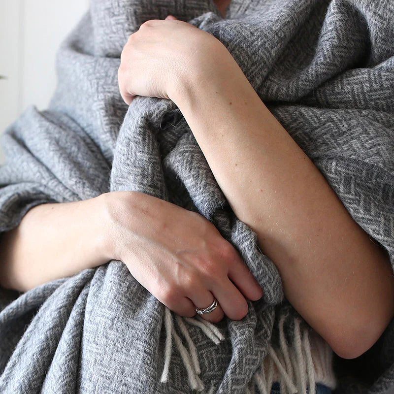 Woman wrapped in grey throw This sustainable and oh so soft basket-weave design is a modern twist on a traditional look. Super soft Alpaca wool is sustainable and beautiful! Did you know that Alpaca fibres are softer, warmer and more durable than other natural fibres? And, Alpaca fibres are smooth so there is less pilling and look new for a long time. Made of 55% Alpaca 45% Wool oversized at 55x78" Designed in Canada and crafted in Peru heavy-weight at 970 GSM