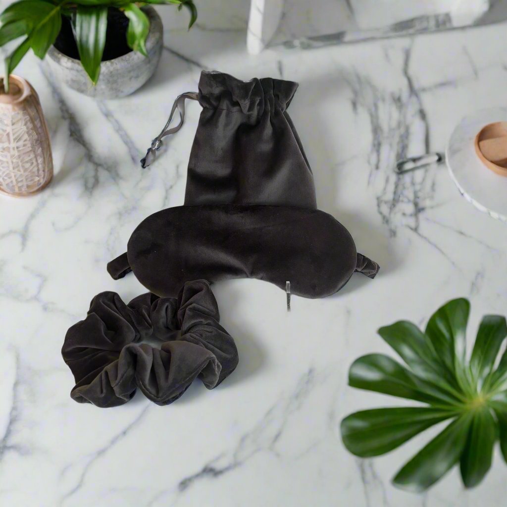 The Sleep Mask and Scrunchie Gift Set features a comfy, eco-friendly design made from luxurious dark grey velvet. Made with soft layers of cotton batting, this sleep mask offers a dreamy night's rest. Plus, it comes with a matching scrunchie and convenient carry bag for your glasses or favorite aromatherapy. Upgrade your sleeping experience and indulge in the luxurious comfort of this gift set!