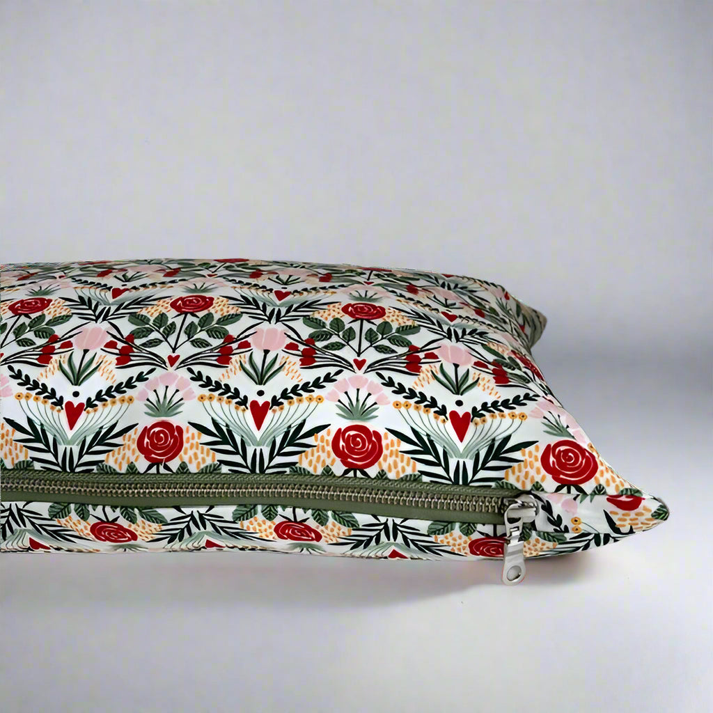 Flowers and hearts organic cotton Love lumbar pillow.  Made with love in Canada, this whimsical pillow adds a touch of fun and comfort! Just the right size to tuck under your neck, it is oh-so-soft and perfect for reading or napping. 10 x 18 inches