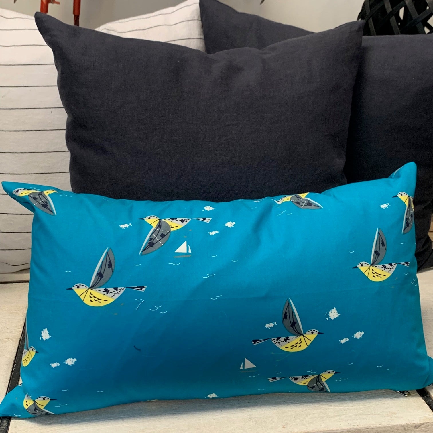 This soft organic cotton pillow cover depicts Charlie Harper's vibrant Caribbean Cruisers in a deep turquoise that will transport you to the sunny seas. This pillow has an exposed, creamy white zipper that contrasts beautifully with these striking shade of the blue with pops of yellow and black.  100% Organic Cotton, handmade in Canada.  Size 14" x 20";  Machine wash warm, low heat dryer  Made to order.