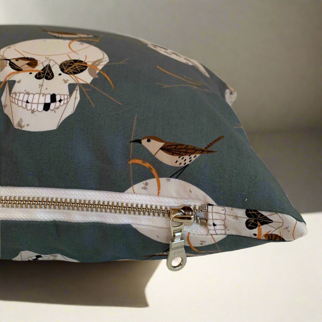 Have fun with your Halloween decor with this playful organic cotton pillow featuring Charlie Harper's spooky Skull and Wren design. The exposed white zipper adds a unique touch against the skulls on a dark grey background. Handcrafted in Canada, this pillow is sure to add some spooktacular charm to your home.

Size 12" x 20" - Down alternative insert with 100% cotton cover included