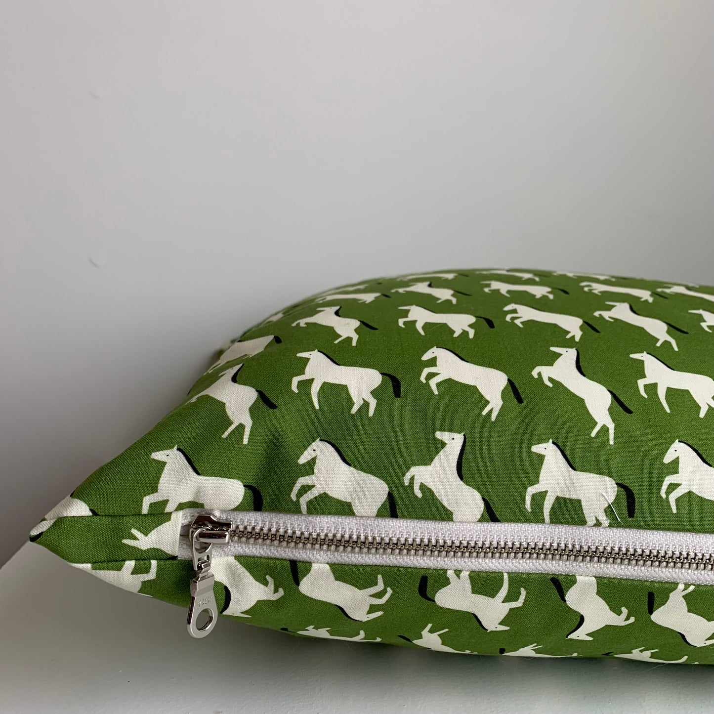 Hand made in Canada, this super cute pony pattern fabric is crafted from GOTS organic cotton. Its softness is unbeatable, and the exposed cream zipper adds a unique touch that pairs perfectly with the vibrant green and bold black accents; Introduce a little whimsy and fun to your home, cottage, bunkie, or sunroom. Size 14 x 20 inches