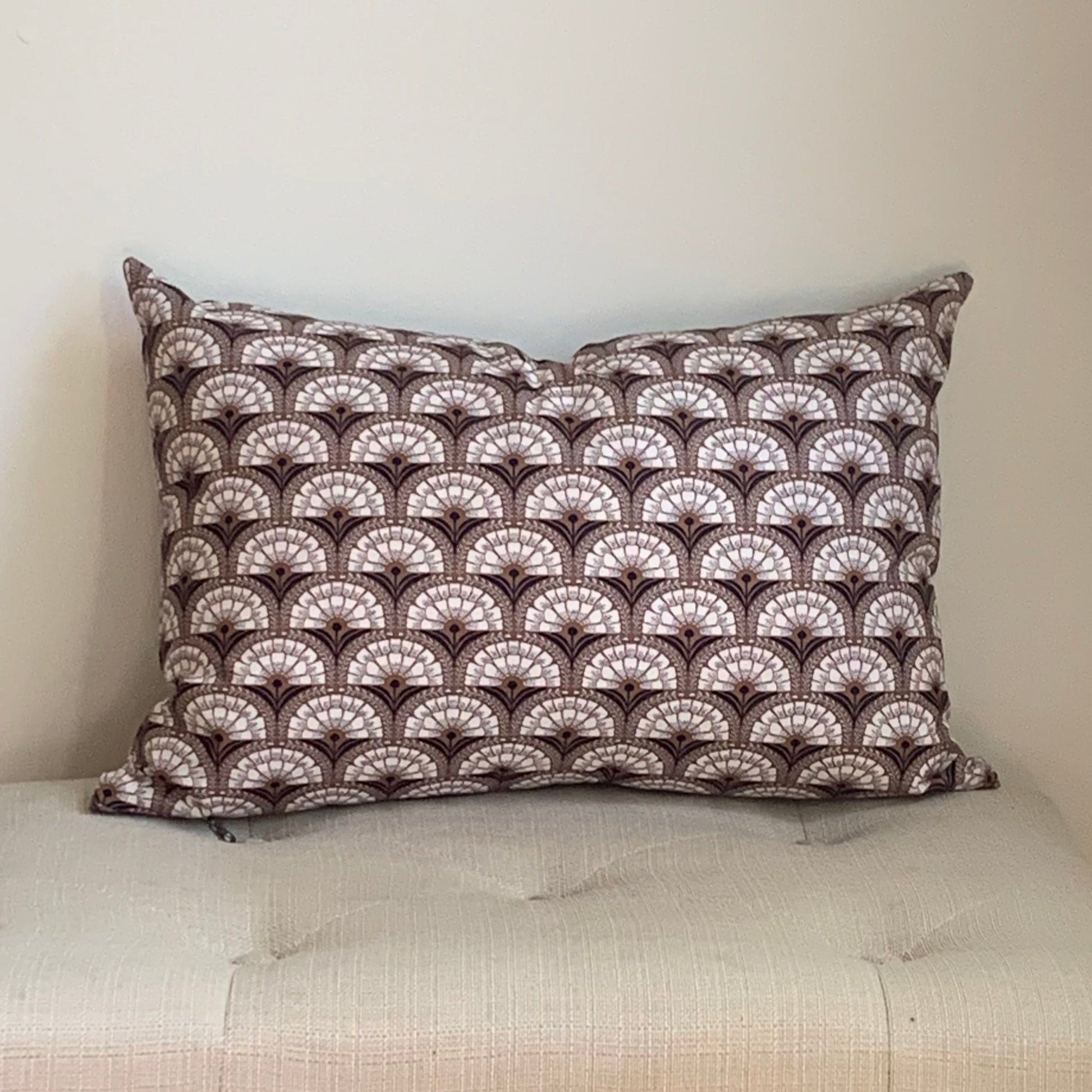 Organic cotton decorative pillow with a geometric pattern on a beige bench against a neutral wall.