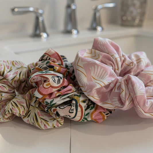 Three floral-patterned scrunchies on a white surface.
