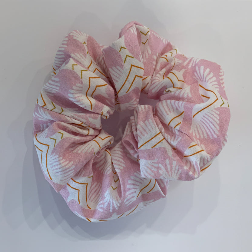 Pink scrunchie with white and gold patterns on a white background