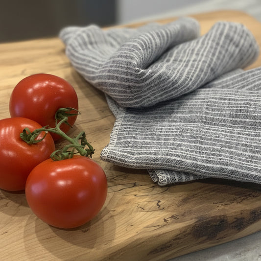 cutting board and tomatoes with Amara NoPaper Towels bring sustainable style to your kitchen. Black with natural stripes, these towels are crafted in Canada from European Flax–certified 100% linen and stonewashed for softness. This set of 4 offers a durable alternative to disposables. Naturally absorbent and quick-drying, they're made to last for years. At 170 gsm weight, they're perfect for drying dishes or everyday kitchen tasks.&nbsp;