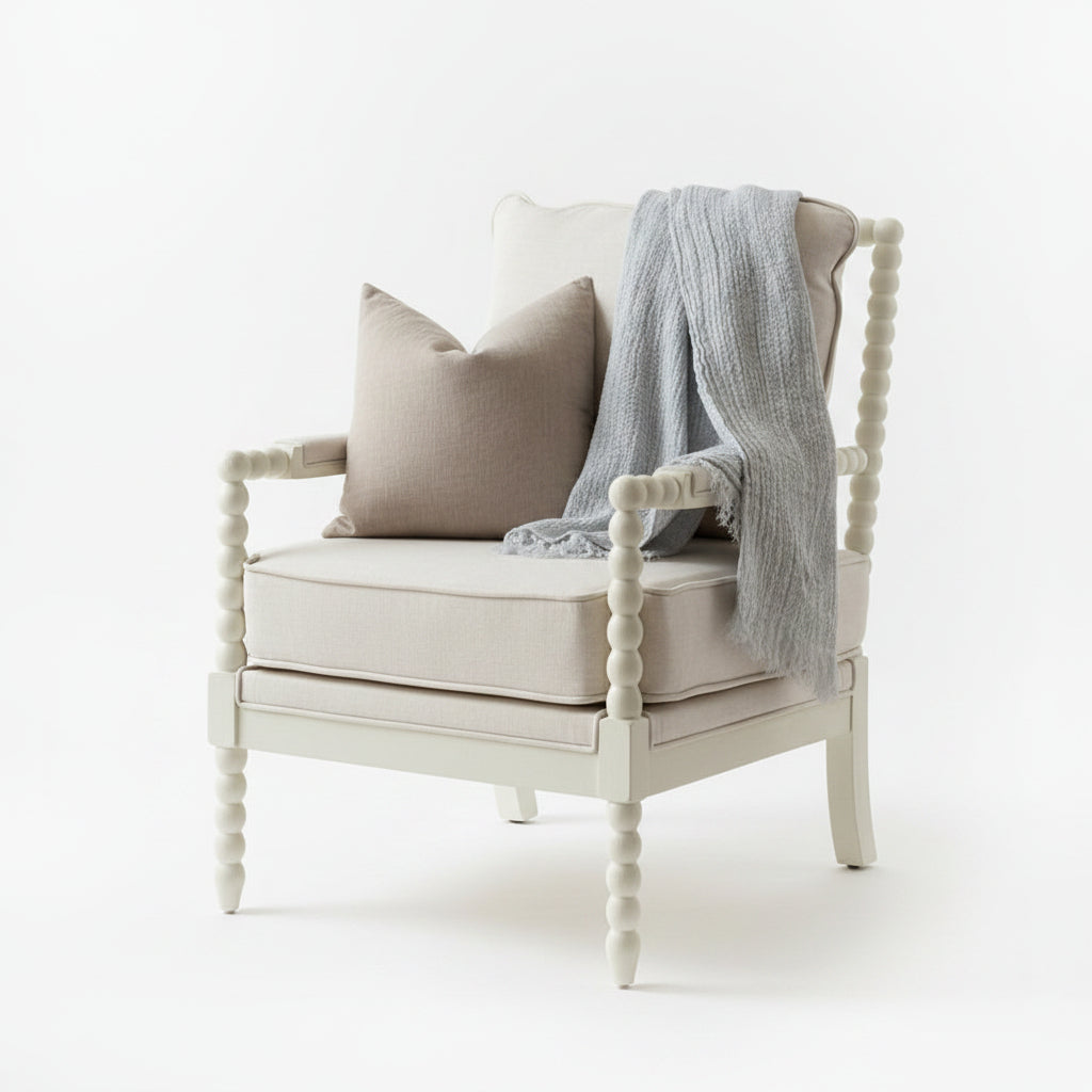 A light mineral blue textured linen throw blanket draped over the back, set on a hardwood floor in front of a window.
