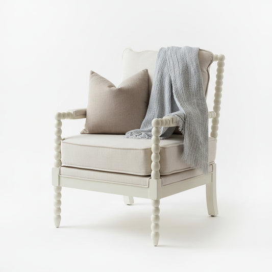 A light mineral blue textured linen throw blanket draped over the back, set on a hardwood floor in front of a window.